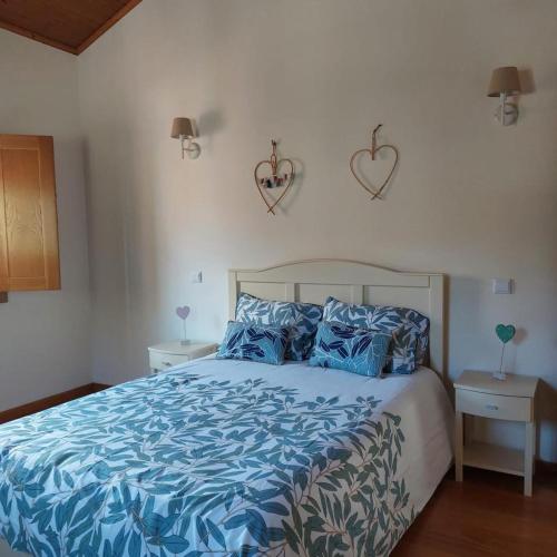 a bedroom with a bed with blue sheets and hearts on the wall at Quinta Vale do Nox in Serrazes