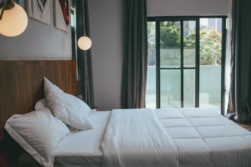 a bed with white sheets and pillows next to a window at Burundi Palace Boutique Hotel in Bujumbura
