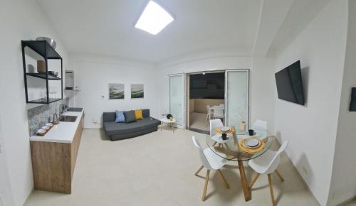 una sala de estar blanca con mesa de cristal y sillas en Mediterraneo RELAX HOUSES en Marina di Ragusa