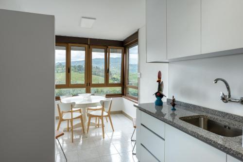 een keuken met witte kasten en een tafel en stoelen bij Apartamento T3 - D'ouro a Vista in Peso da Régua