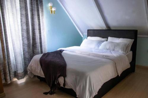 a bedroom with a large bed with white sheets and pillows at Charming 1-Bed Penthouse in Karen Nairobi in Nairobi