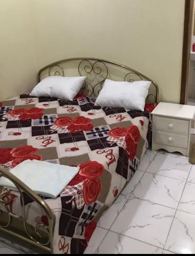 a bed with a quilt with red roses on it at Marie's residence in Medina Suware Kunda