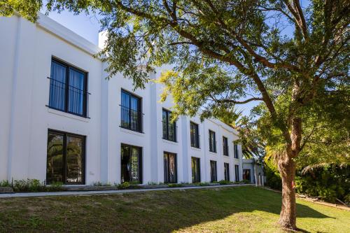 a white building with a tree in front of it at Lord Charles Hotel in Somerset West