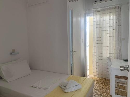 a white bedroom with a bed and a window at Korali Hotel in Antiparos Town