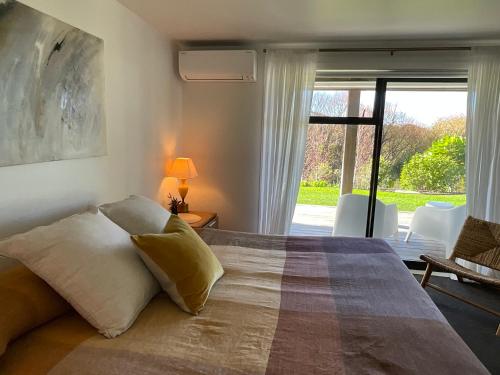 a bedroom with a large bed with a large window at Garden Apartment in Matakana