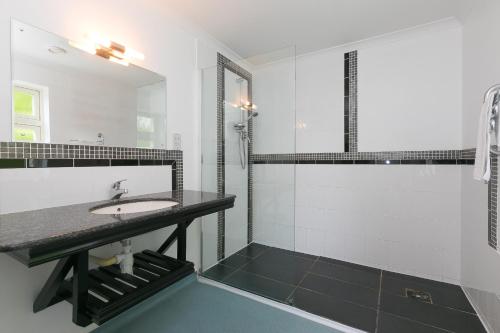 Un baño blanco con lavabo y ducha. en Moonbeams, en St Ives