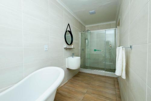 y baño con bañera y ducha acristalada. en Greenshade Lodge, en Johannesburgo
