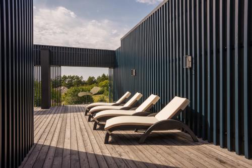 a row of white chairs sitting on a wooden deck at VAIVA Apartments, Palanga in Šventoji
