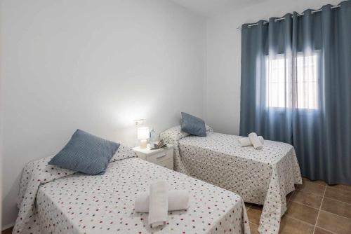two twin beds in a room with blue curtains at Casa Rural Rafael Lantejuela in La Lantejuela