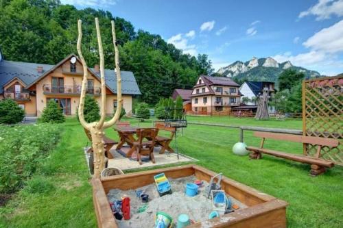 a garden with a sandbox and a table and a table at Wynajem pokoi Natalia in Sromowce Niżne