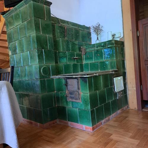 a green tiled wall with a stove in a room at Domek Myśliwski z sauną 