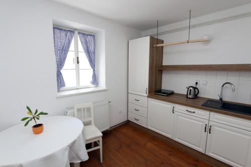 a kitchen with white cabinets and a table and a sink at Penzion Mauritz in Nová Pec