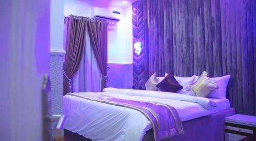 a purple bedroom with a bed with white sheets and pillows at Delimes Hotel in Use
