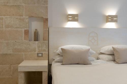 a bedroom with a bed with white pillows and a table at Relais Porta del Sud in Ostuni