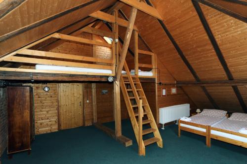 an attic room with a bunk bed and a ladder at Penzion Mauritz in Nová Pec