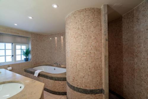 a bathroom with two sinks and a bath tub at High Corner Inn in Ringwood