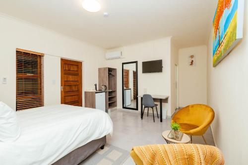 1 dormitorio con 1 cama y escritorio con silla en Greenshade Lodge, en Johannesburgo