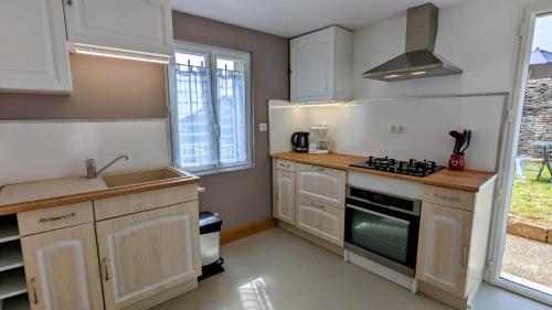 a kitchen with a sink and a stove top oven at Le Cocon des Hautes-Côtes in Fussey