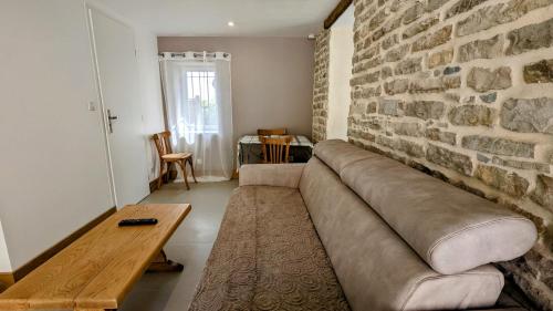 a living room with a couch and a brick wall at Le Cocon des Hautes-Côtes in Fussey