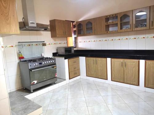 a kitchen with wooden cabinets and a stove at Good Times in Kampala