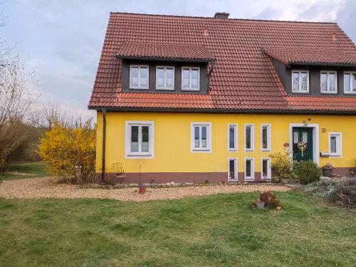 una casa amarilla con techo rojo en Ferienwohnung NatuRaum en Gräfenberg