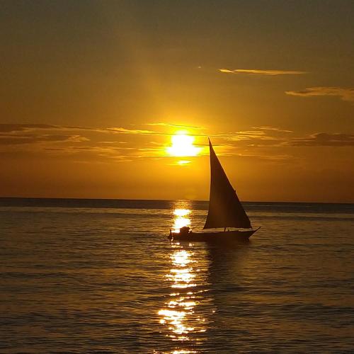 a sail boat in the ocean at sunset at Furaha Rena -Kendwa in Kendwa