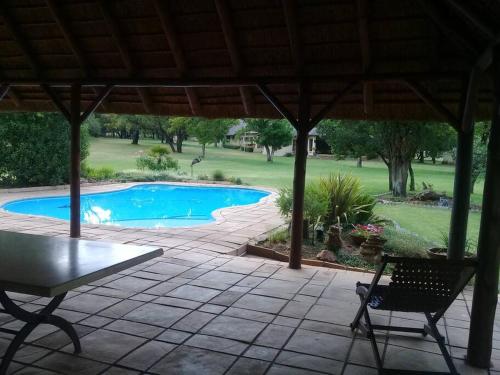 a patio with a table and chairs next to a pool at Gentleman's Estate on the Vaal River in Vanderbijlpark
