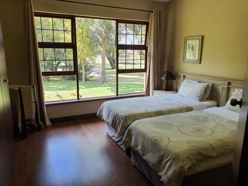 a bedroom with two beds and a large window at Gentleman's Estate on the Vaal River in Vanderbijlpark