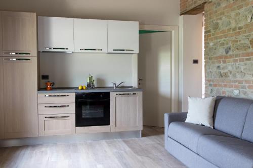 a kitchen with white cabinets and a couch in a room at Agriturismo La Ratta in Vernasca