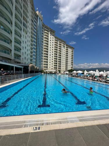 2 personas nadando en una gran piscina con edificios en Alanya gold city hotel main building 3 bedroom apartment, en Alanya