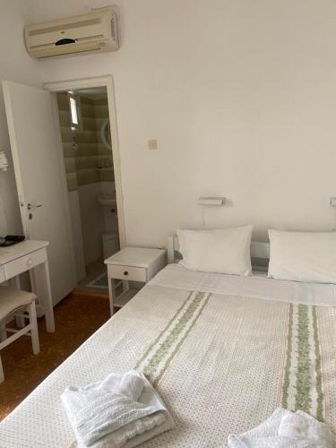 a white bedroom with a bed with two towels on it at Korali Hotel in Antiparos Town
