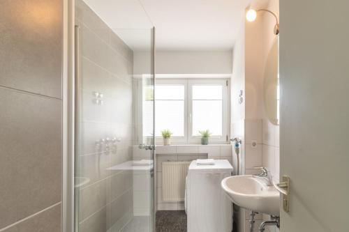 a white bathroom with a sink and a shower at Unique: Geräumige 4 Zimmerwohnung in Tuttlingen mit Sauna, Fitness und Netflix OG in Tuttlingen