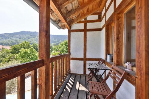 um alpendre de uma cabina com duas cadeiras e uma mesa em Le Manoir des Sens - Forêt de Bergheim em Thannenkirch