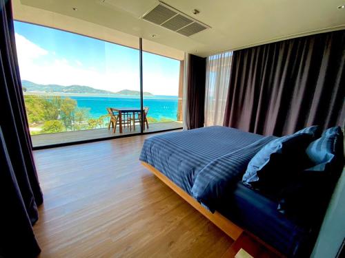 um quarto com uma cama e uma grande janela em The Naka Phuket, a Member of Design Hotels - SHA Extra Plus em Praia de Kamala