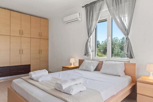 a bedroom with a large white bed with a window at Agathi Sun Set in Rhodes Town
