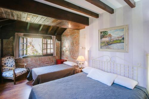 a hotel room with two beds and a chair at La Posada de Langre in Langre