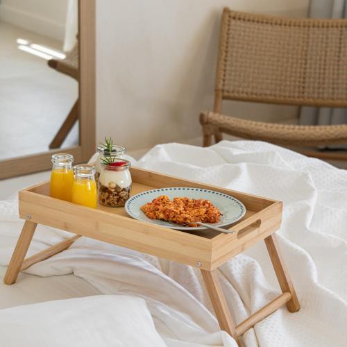 a tray with a plate of food on a table on a bed at Etesians Suites & Villas in Super Paradise Beach