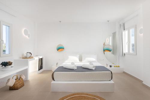 a white bedroom with a bed and a kitchen at VOCA HOTEL & SUITES in Kamari