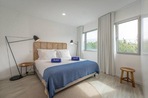 a bedroom with a bed and two tables and two windows at Oceanside East in Ponta Delgada