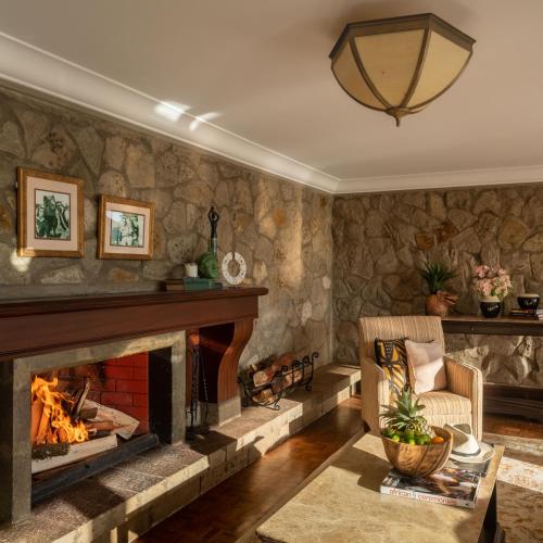 a living room with a fireplace and a chair at Fairmont Mount Kenya Safari Club in Nanyuki
