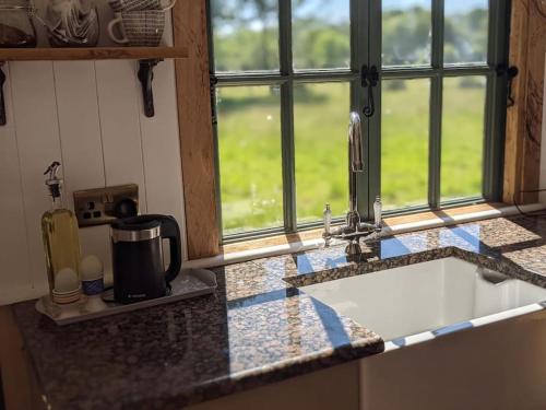 encimera de cocina con fregadero y ventana en Kenny’s Hut en Cowfold