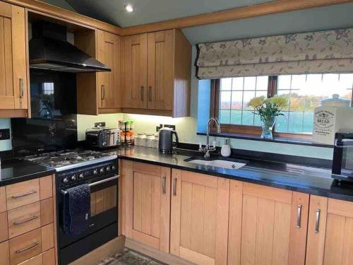 a kitchen with wooden cabinets and a stove top oven at The Old Telephone Exchange - surrounded by fields! in Harrogate