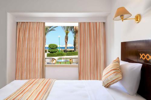 Schlafzimmer mit einem Bett und einem Fenster mit Aussicht in der Unterkunft Menaville Resort in Hurghada