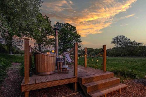 terraza de madera con bañera de hidromasaje y columpio en Kenny’s Hut en Cowfold