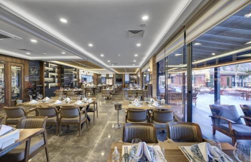 a restaurant with wooden tables and chairs and windows at Porto Amore Club Hotel in Alanya