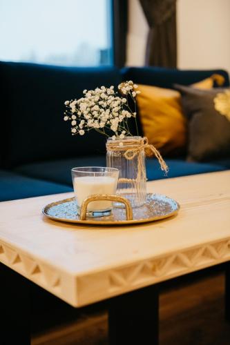 a table with a glass vase with flowers on it at Apartamenty Górajski Spa in Kościelisko