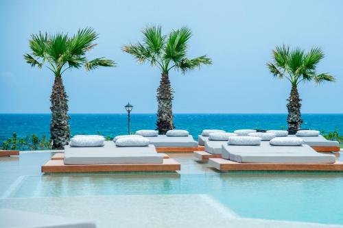 um resort com palmeiras e uma piscina em SENSEANA Sea Side Resort & Aquadventure em Hersonissos