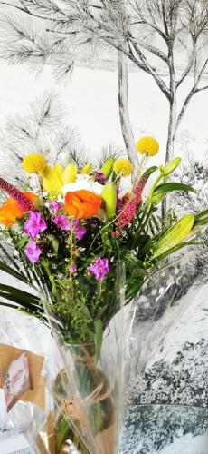 a glass vase filled with colorful flowers on a table at L'Essentiel - Love 5 Etoiles in Talmont