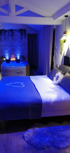 a bedroom with a large bed with blue lighting at L'Essentiel - Love 5 Etoiles in Talmont