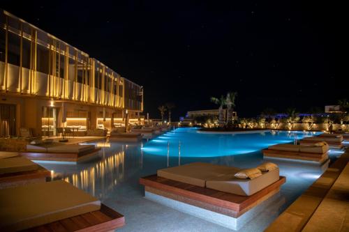 a swimming pool at night with chaise lounges at SENSEANA Sea Side Resort & Aquadventure in Hersonissos